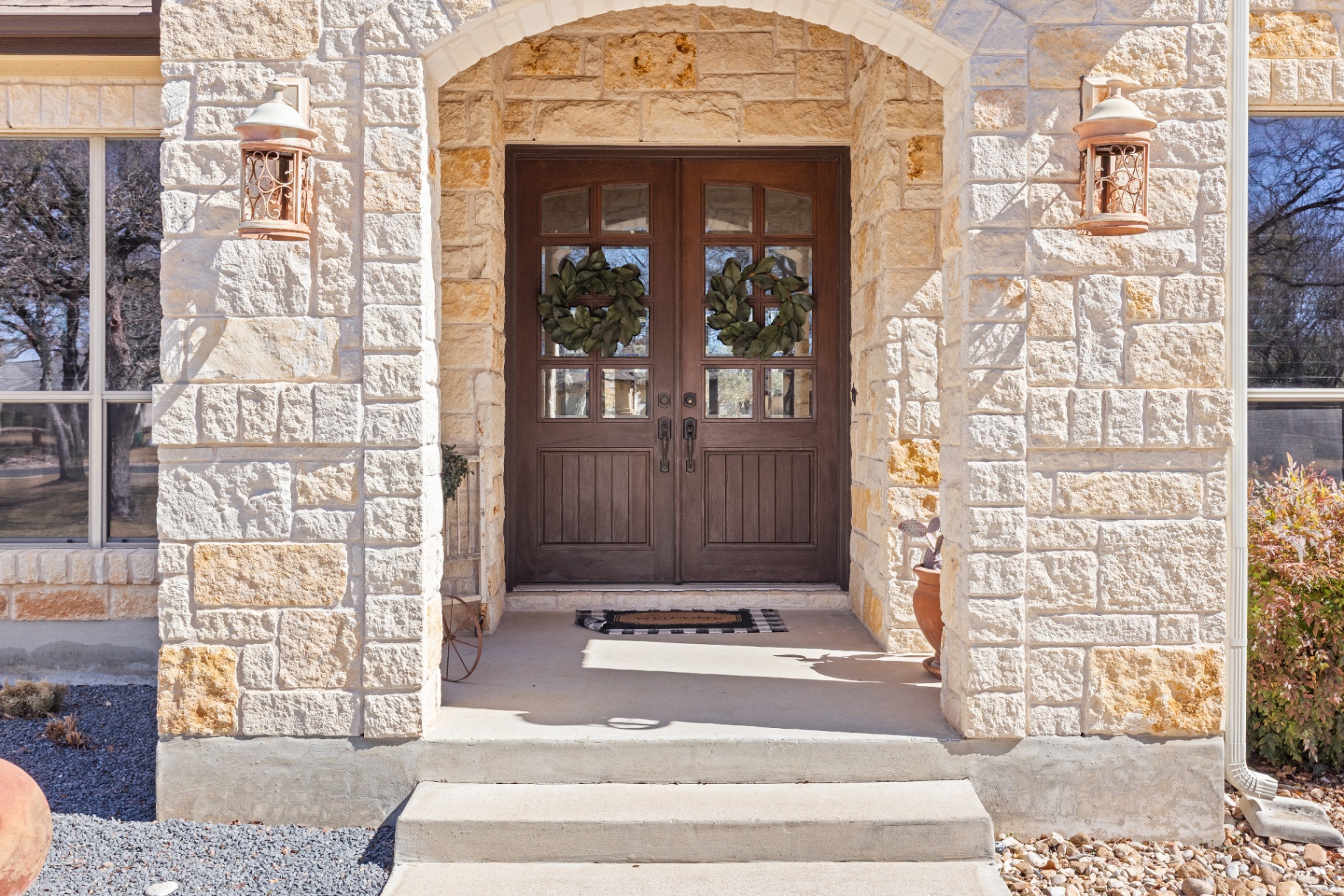 Custom arched double front door with stone surround and copper lanterns