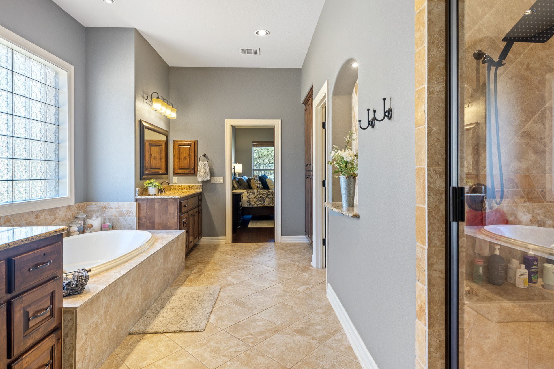 Primary bathroom showing walk-in shower and soaking tub with view to bedroom