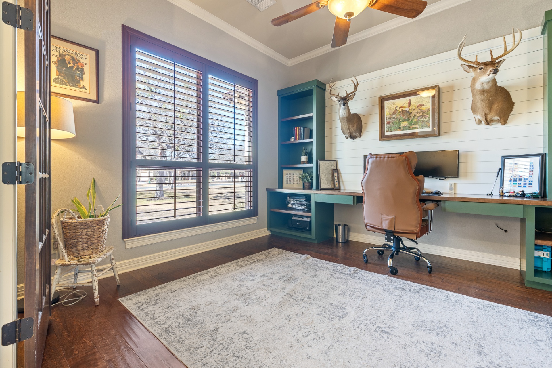 Office showing large window with plantation shutters and built-in workspace
